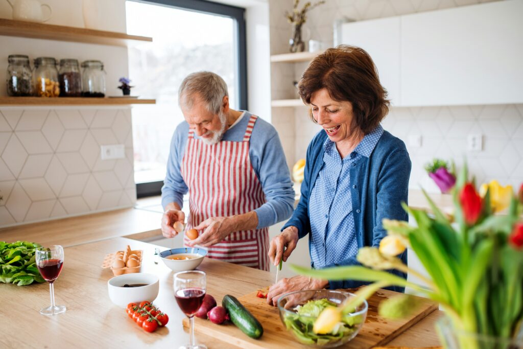 Older man and woman cooking a healthy meal together in the kitchen, preparing vegetables for a family managing diabetes