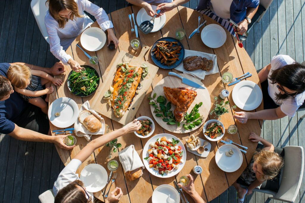 Family gathered around a holiday table with roasted turkey, salmon, vegetables, and salad for diabetes-friendly holiday meal planning