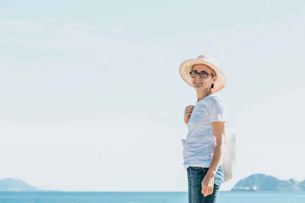Older woman standing outdoors near the ocean on a humid, hazy day
