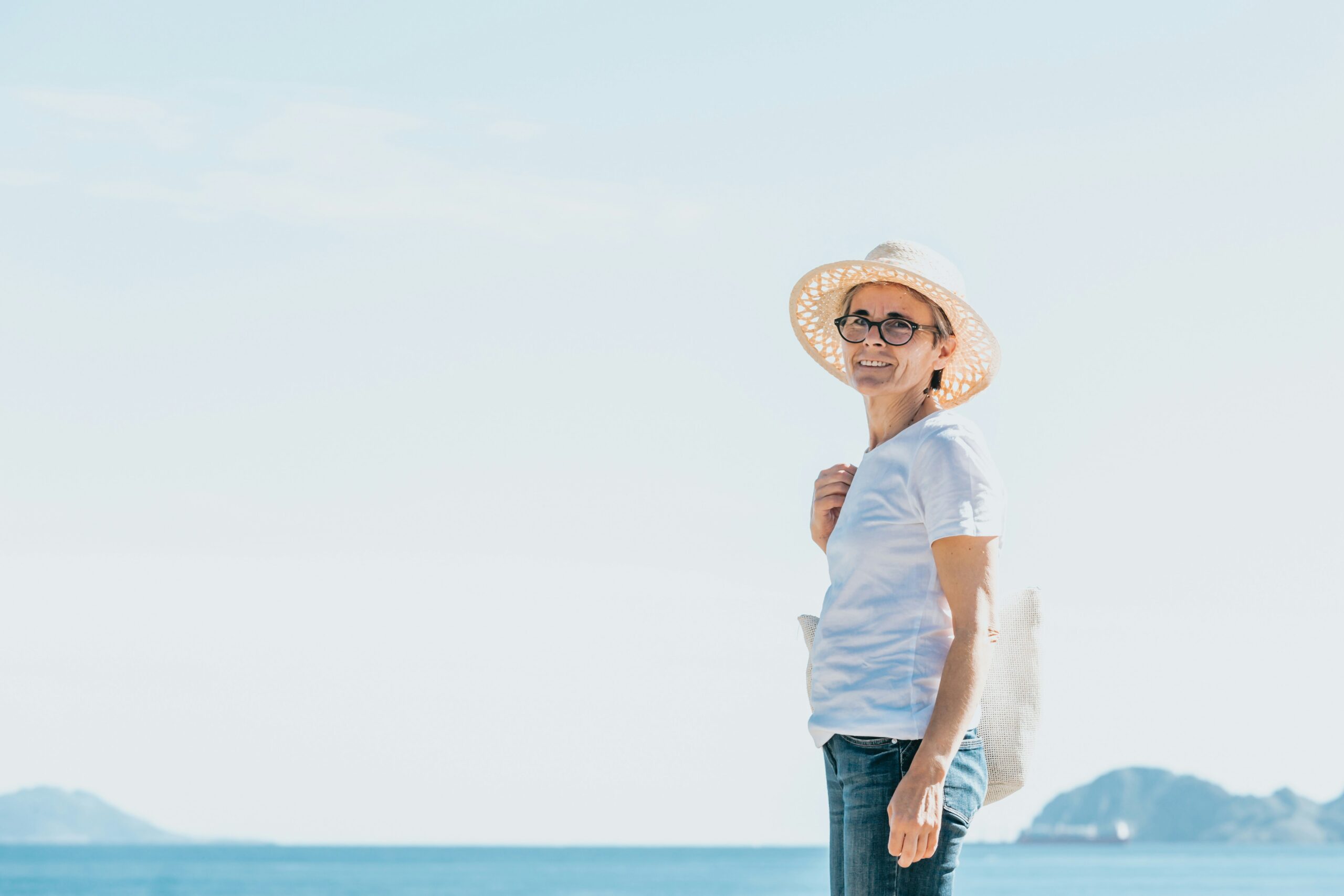 Older woman standing outdoors near the ocean on a humid, hazy day