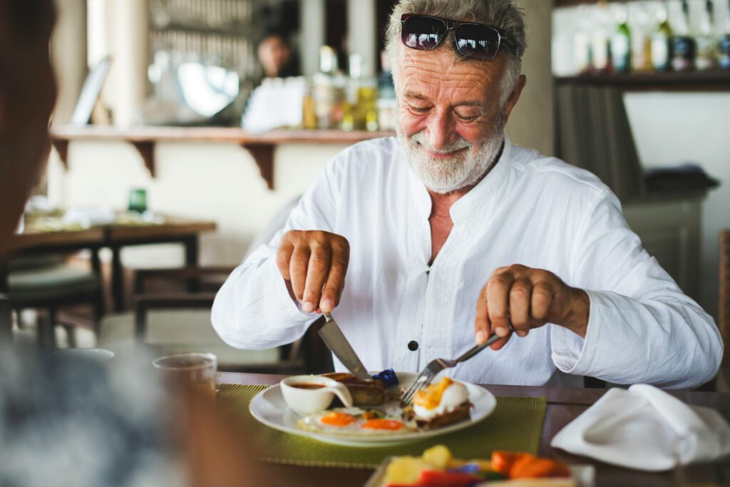 Older man enjoying a balanced breakfast, meeting his changing nutritional needs after 65