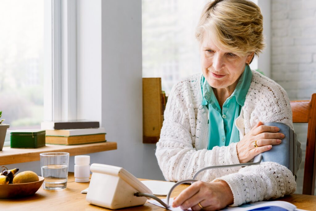 Older woman living alone with a chronic illness checking her blood pressure at home