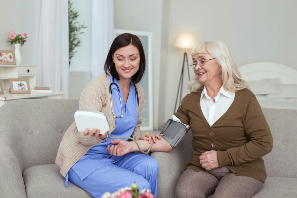 Home care nurse checking an elderly woman's blood pressure to monitor heart health and hypertension risk