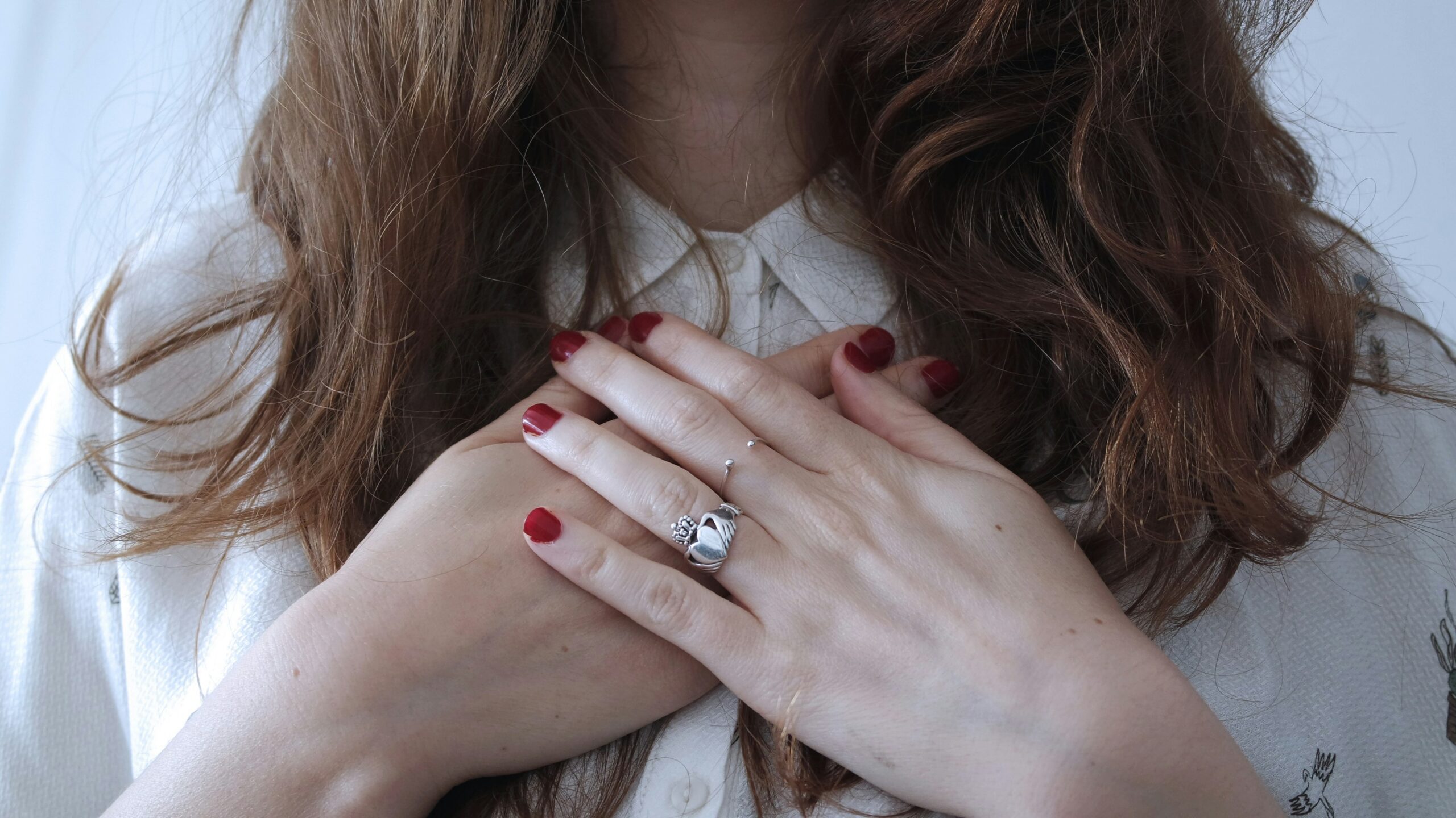 Woman with hands crossed over her heart, reflecting concern about genetic heart disease risk